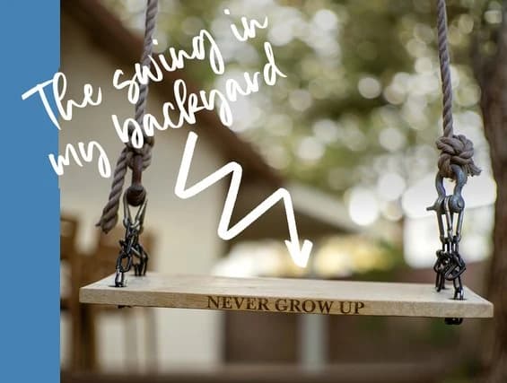 A wooden swing engraved “Never grow up” hanging in a backyard