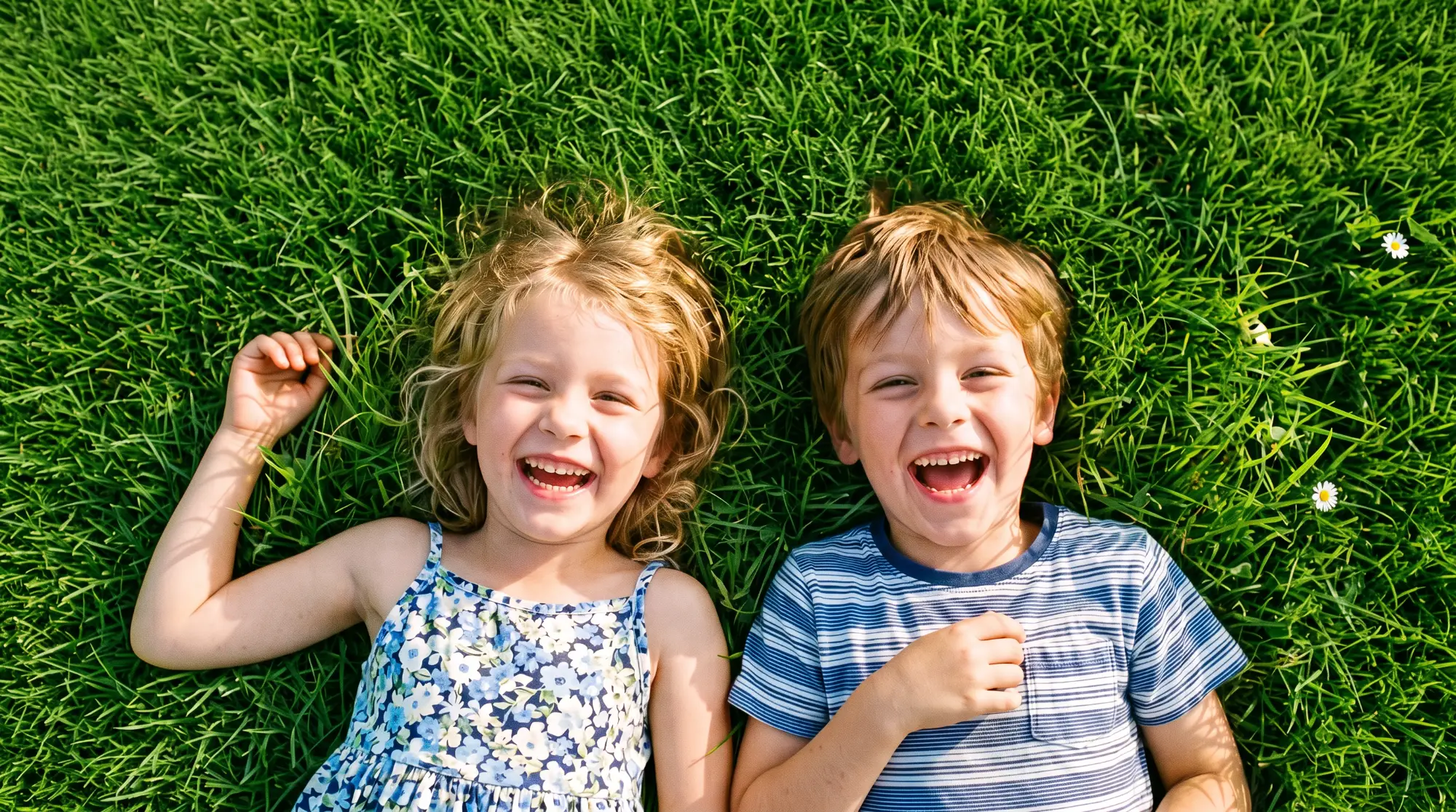 Two kids lying in the grass, laughing